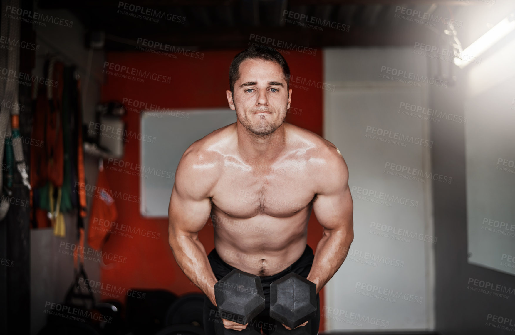 Buy stock photo Cropped shot of a handsome and muscular young man working out with dumbbells in the gym