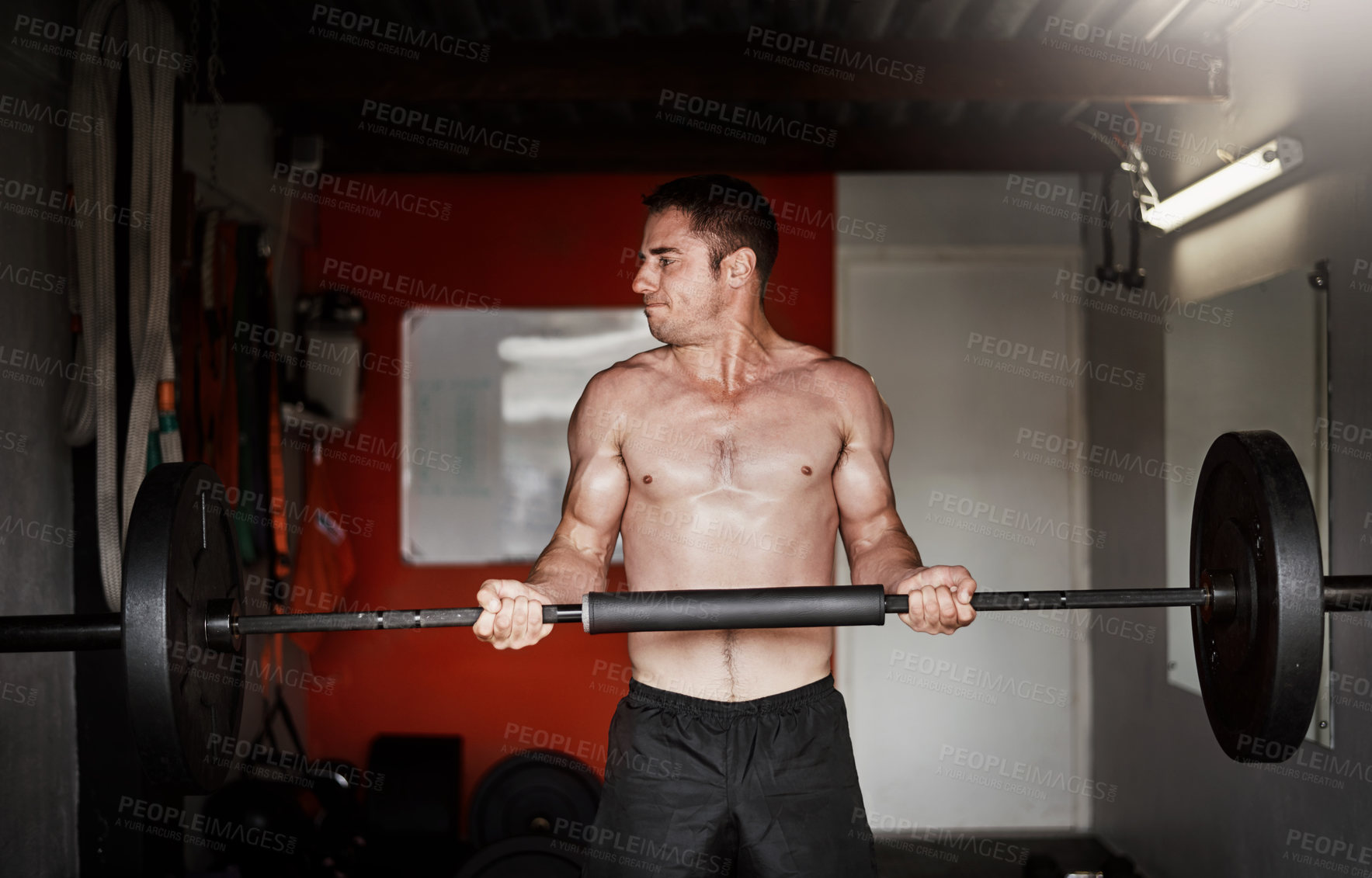 Buy stock photo Cropped shot of a handsome and muscular young man working out with a barbell in the gym