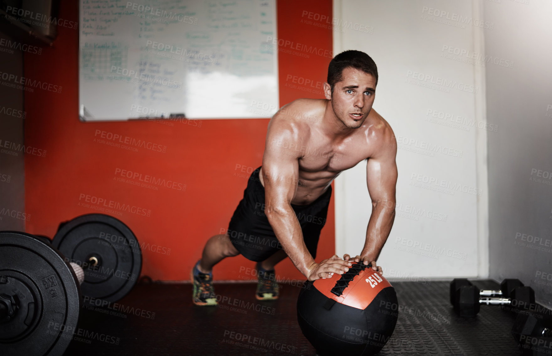 Buy stock photo Full length shot of a handsome and muscular young man working out with a medicine ball in the gym