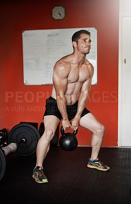 Buy stock photo Full length shot of a handsome and muscular young man working out with a kettle bell in the gym