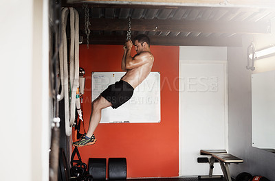 Buy stock photo Full length shot of a handsome and muscular young man doing pullups using a chain in the gym