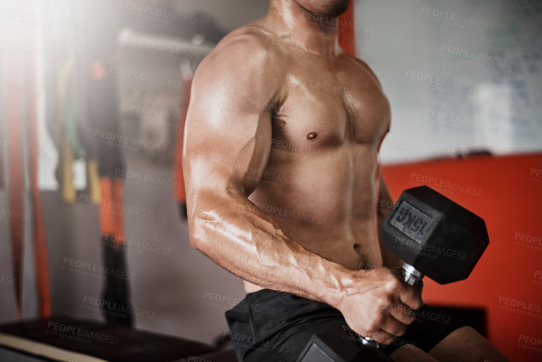 Buy stock photo Cropped shot of an unrecognizable muscular young man working out with a dumbbell in the gym