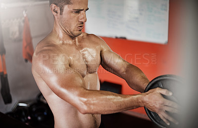 Buy stock photo Cropped shot of a handsome and muscular young man working out with a weight in the gym