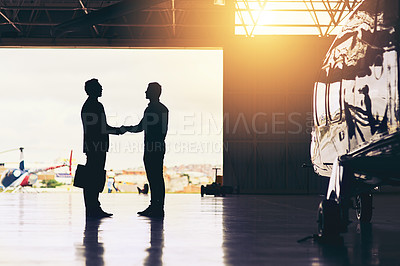 Buy stock photo Full length shot of two unrecognizable businessmen shaking hands while standing in a hanger at the airport