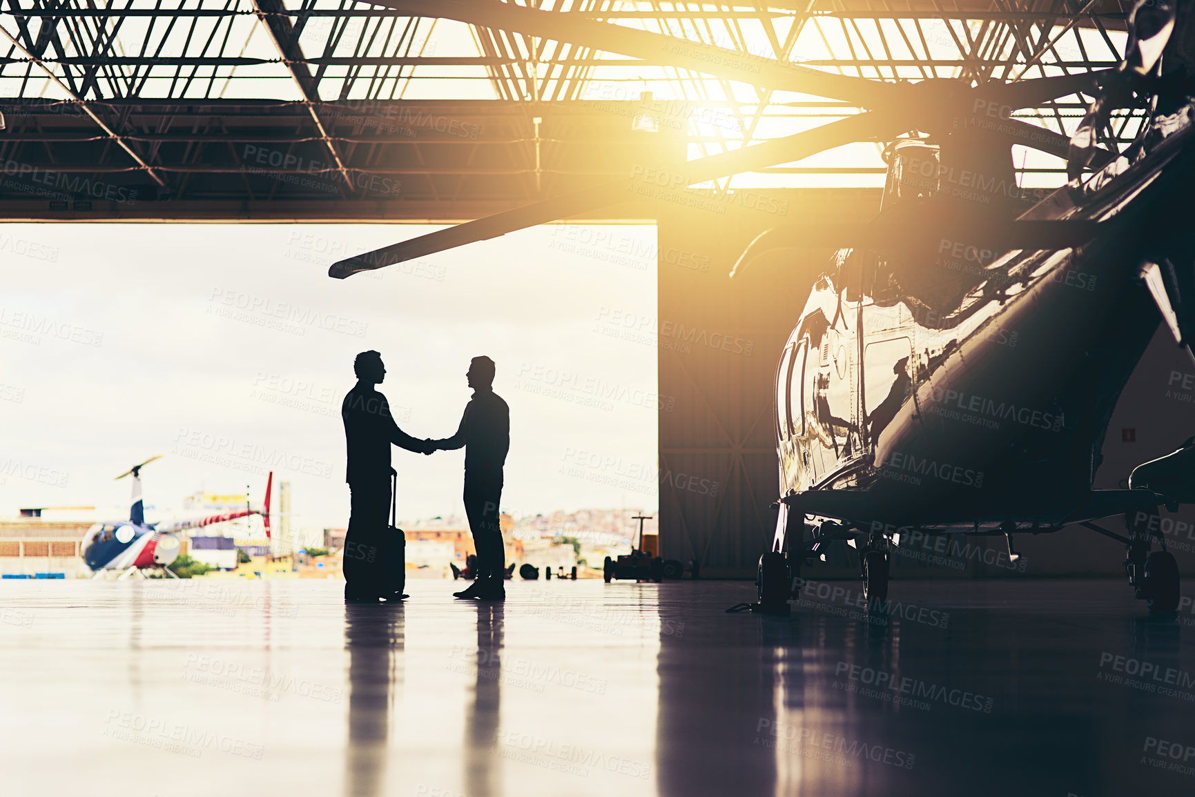 Buy stock photo Full length shot of two unrecognizable businessmen shaking hands while standing in a hanger at the airport