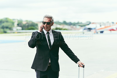 Buy stock photo Cropped shot of a handsome mature businessman walking with his luggage outside of the airport