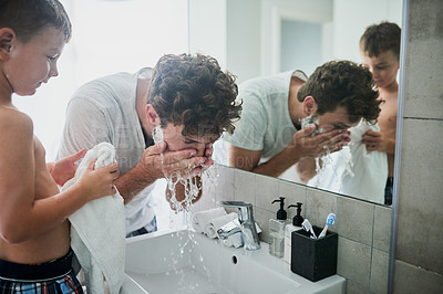 Buy stock photo Shot of a little boy watching his father rinse his face while shaving in the bathroom at home