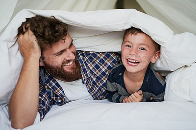 Buy stock photo Cropped portrait of an adorable little boy and his father lying on the bed at home