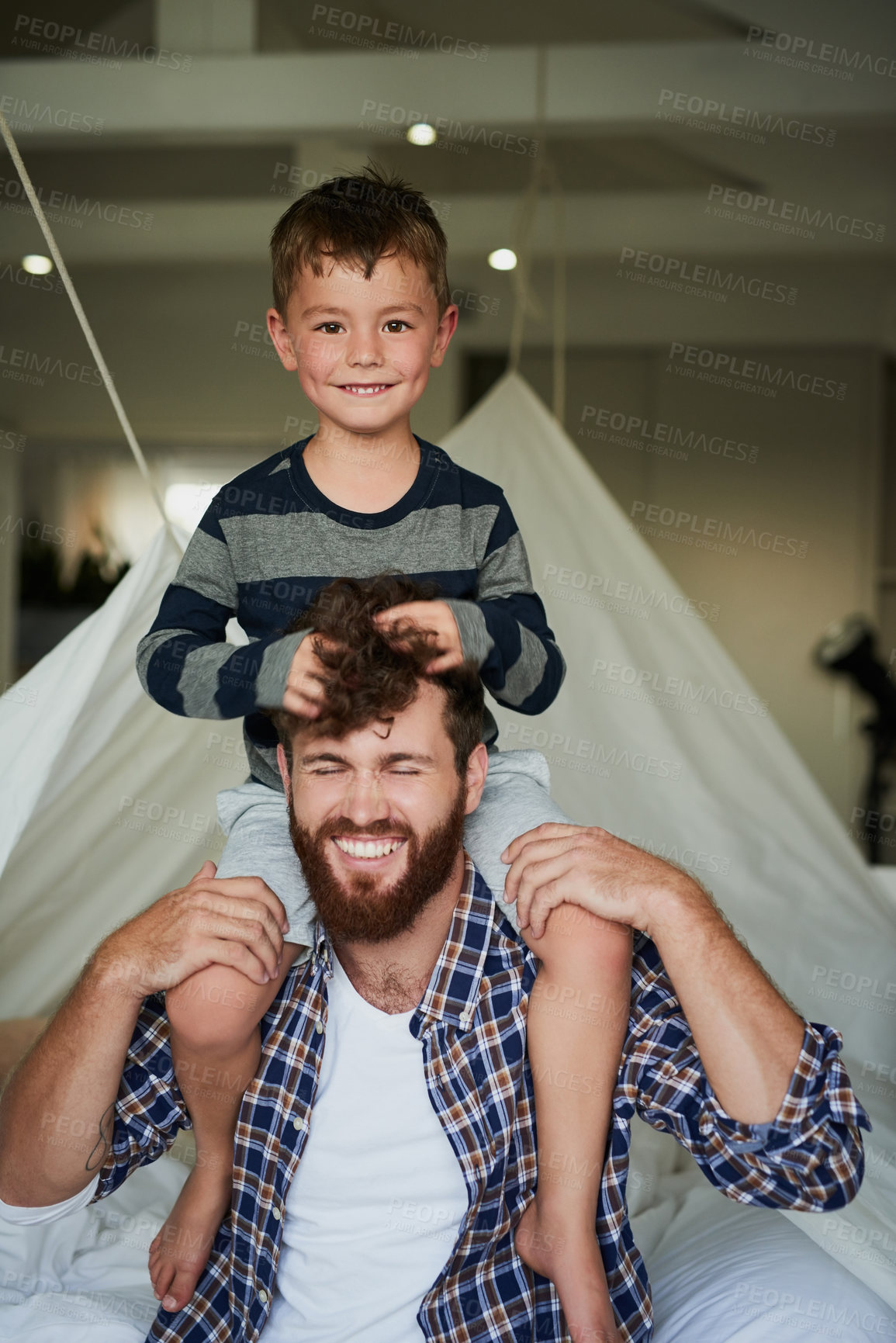 Buy stock photo Cropped portrait of an adorable little boy sitting on his dad's shoulders while sitting on the bed at home