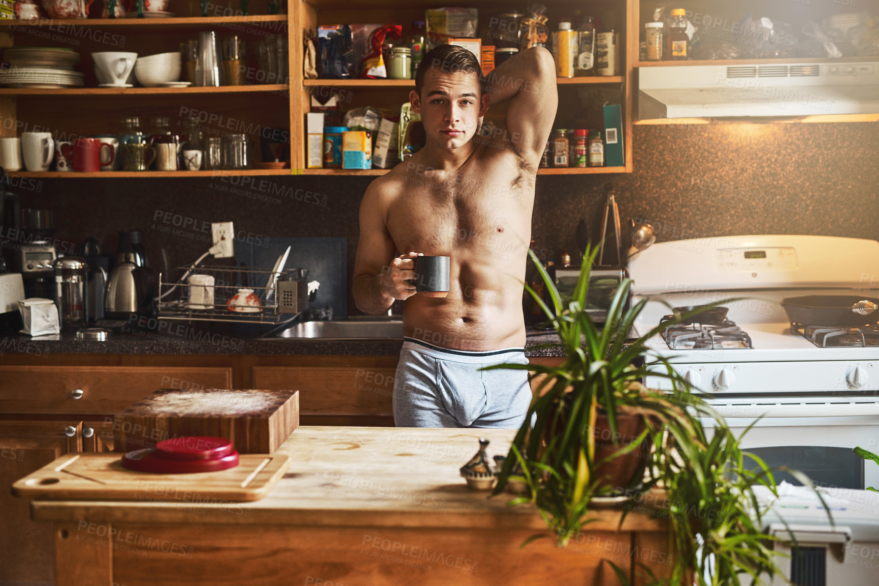 Buy stock photo Cropped shot of a handsome young shirtless man drinking a cup of coffee in the kitchen at home
