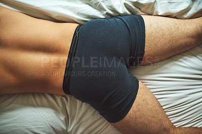 Buy stock photo High angle shot of an unrecognizable shirtless man lying on his bed at home