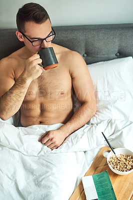 Buy stock photo Cropped shot of a handsome young shirtless man drinking coffee and having breakfast in bed at home