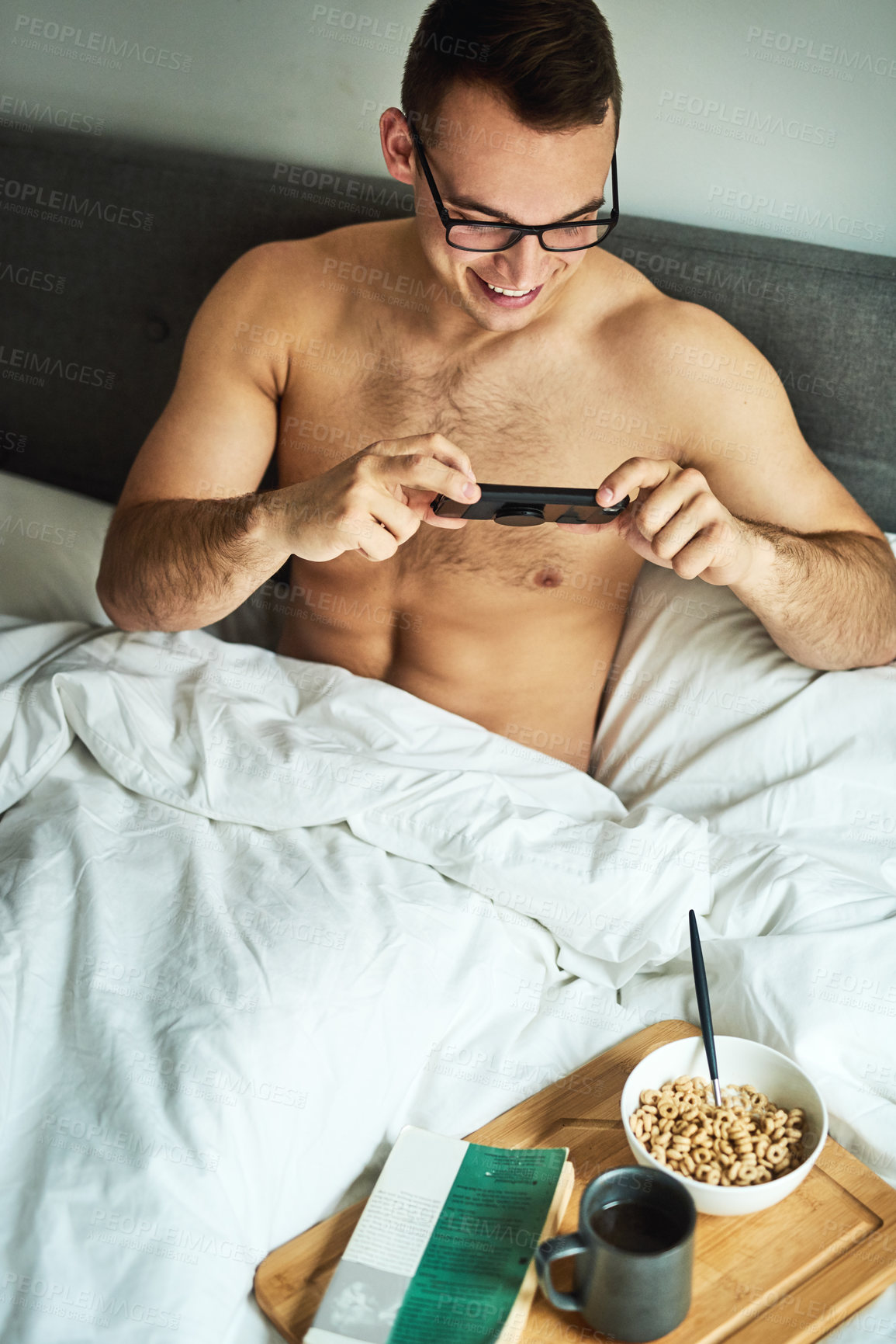Buy stock photo Cropped shot of a handsome young shirtless man taking a picture of his breakfast in bed at home