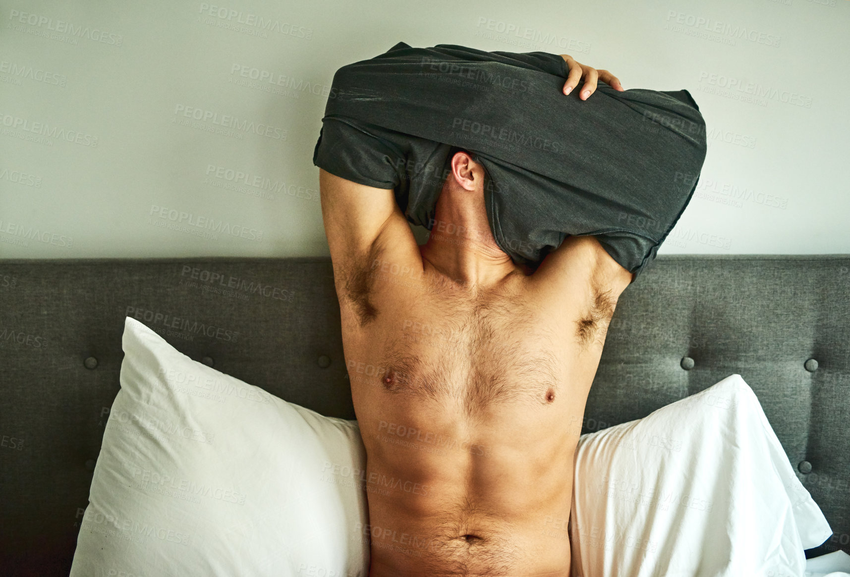Buy stock photo Cropped shot of an unrecognizable man undressing on his bed at home