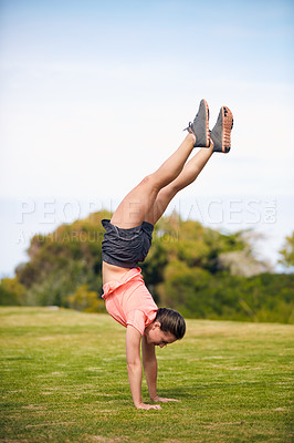 Buy stock photo Shot of a young attractive woman doing a handstand outside