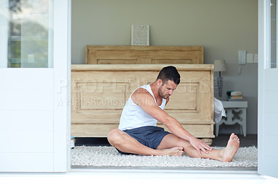 Buy stock photo Shot of a young handsome man stretching at home