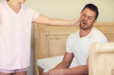 Buy stock photo Cropped shot of an unrecognizable woman slapping her husband across the face in the bedroom at home