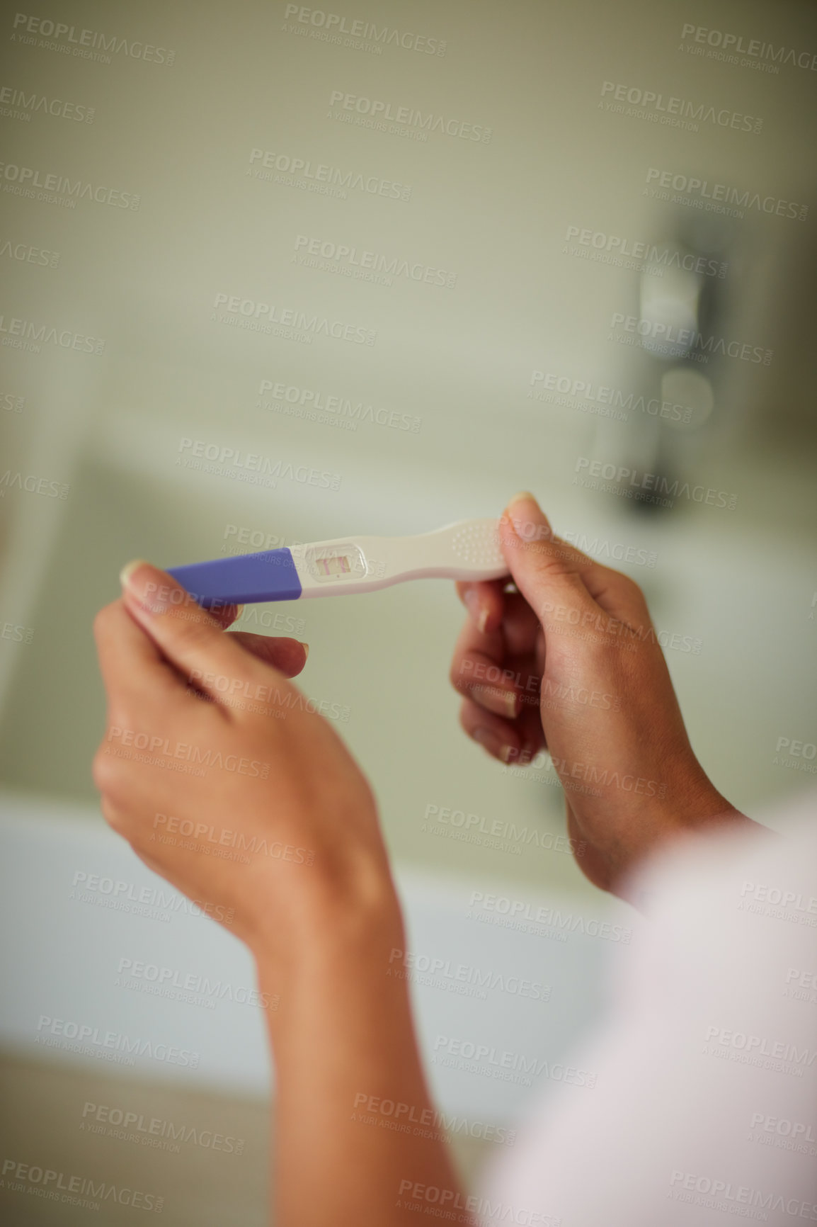 Buy stock photo Cropped shot of an unrecognizable woman holding a pregnancy test in the bathroom at home