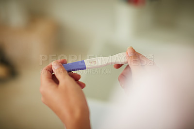 Buy stock photo Cropped shot of an unrecognizable woman holding a pregnancy test in the bathroom at home