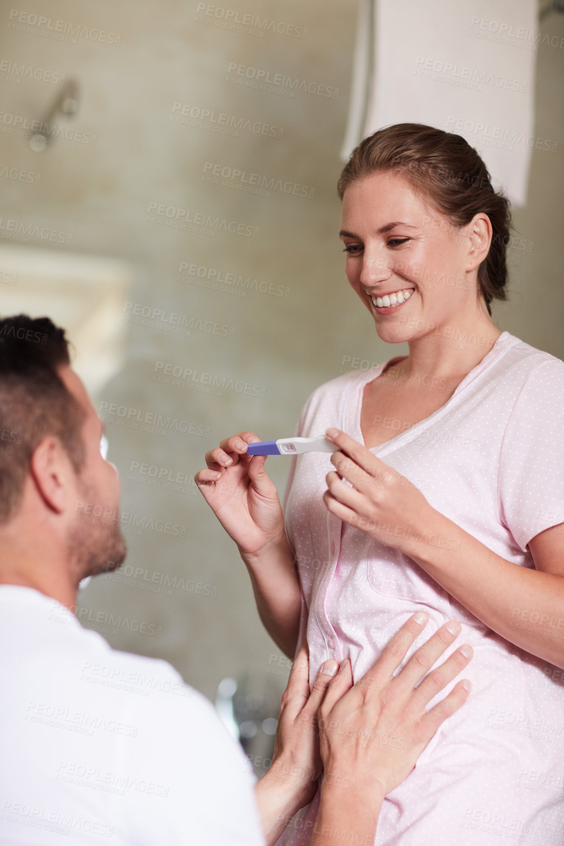 Buy stock photo Cropped shot of a wife showing her husband a pregnancy test in the bathroom at home