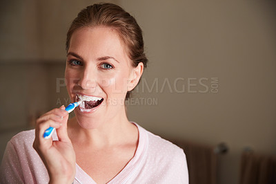Buy stock photo Portrait of a young attractive woman brushing her teeth in the bathroom at home
