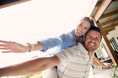 Buy stock photo Cropped shot of a young handsome man giving his beautiful wife a piggyback ride outside
