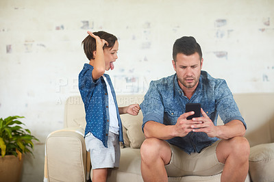 Buy stock photo Shot of a man busy on his phone while his son is seeking for attention