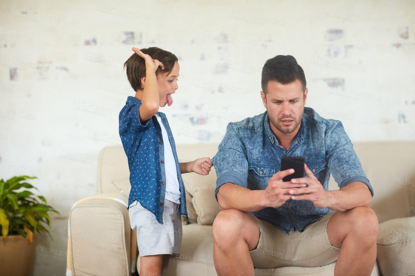 Buy stock photo Shot of a man busy on his phone while his son is seeking for attention