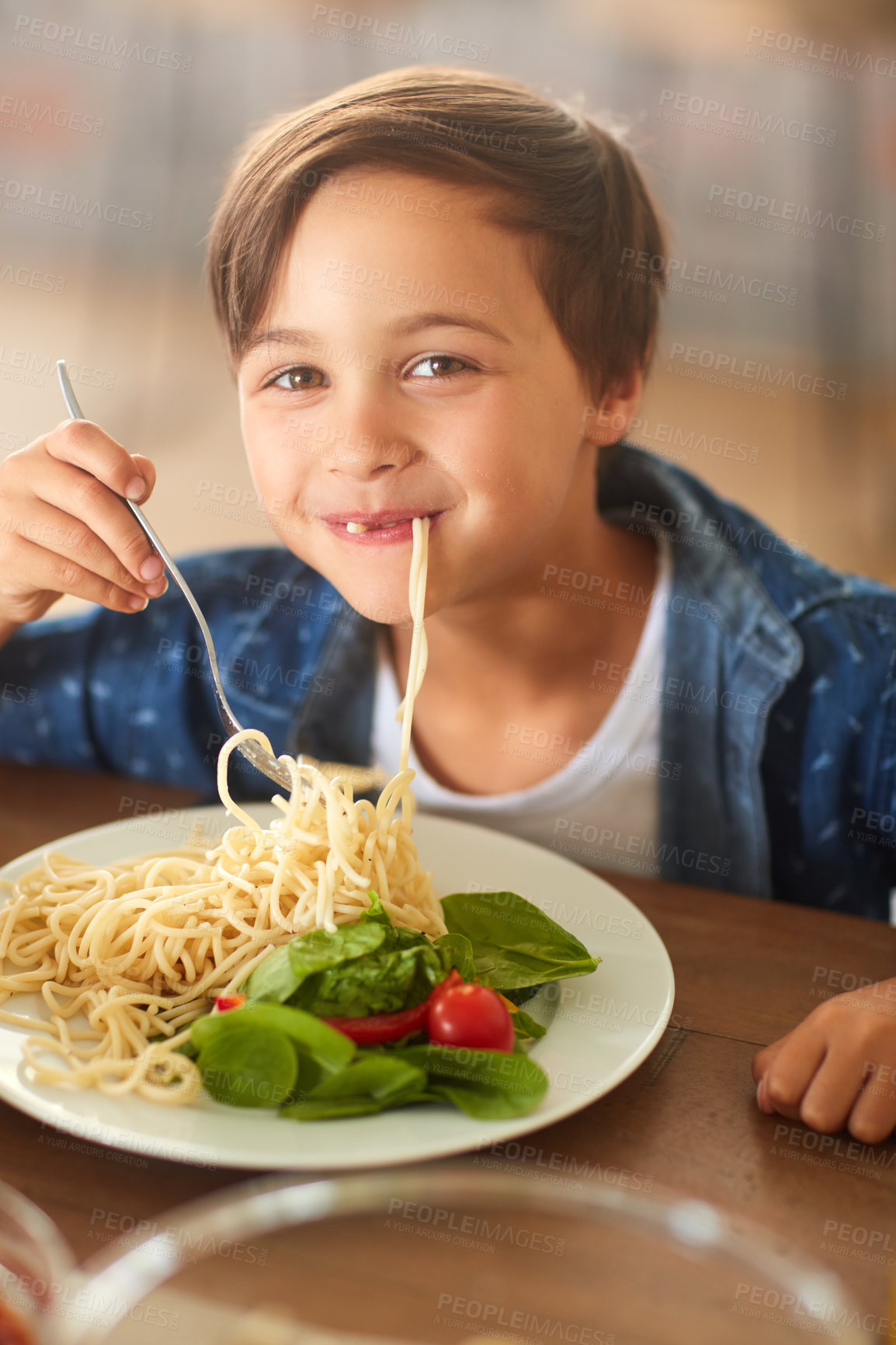 Buy stock photo Cropped shot of an adorable little boy eating his food at home