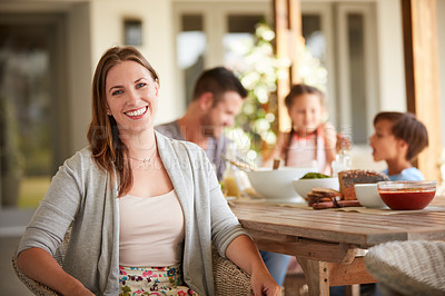 Buy stock photo Defocused shot of a  woman at home with her family sitting in the background