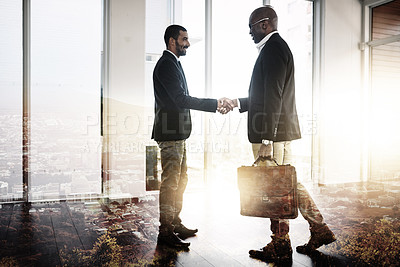 Buy stock photo Full length shot of two businessmen shaking hands in an office superimposed over a city background