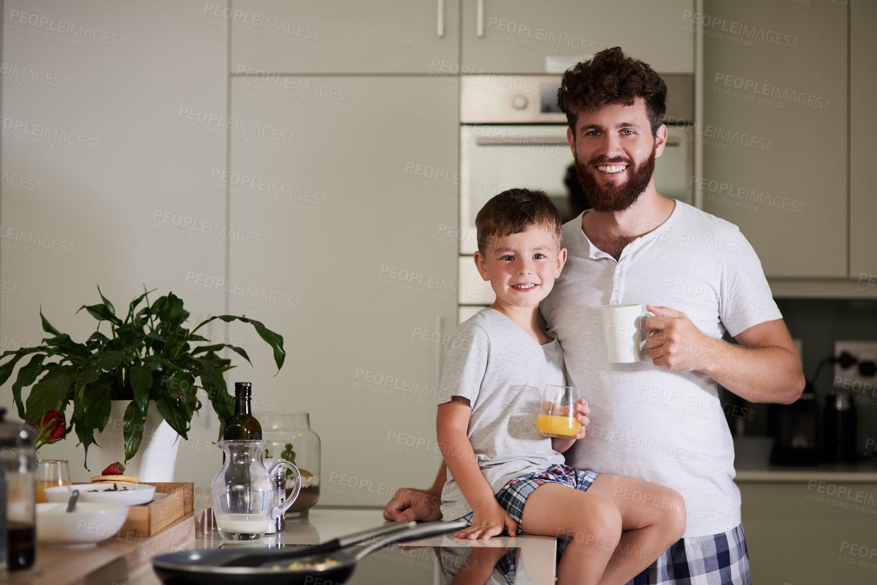 Buy stock photo Shot of an adorable little boy and his father having coffee and juice together at home