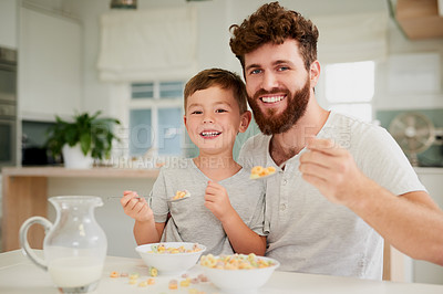 Buy stock photo Shot of an adorable little boy and his father having breakfast together at home