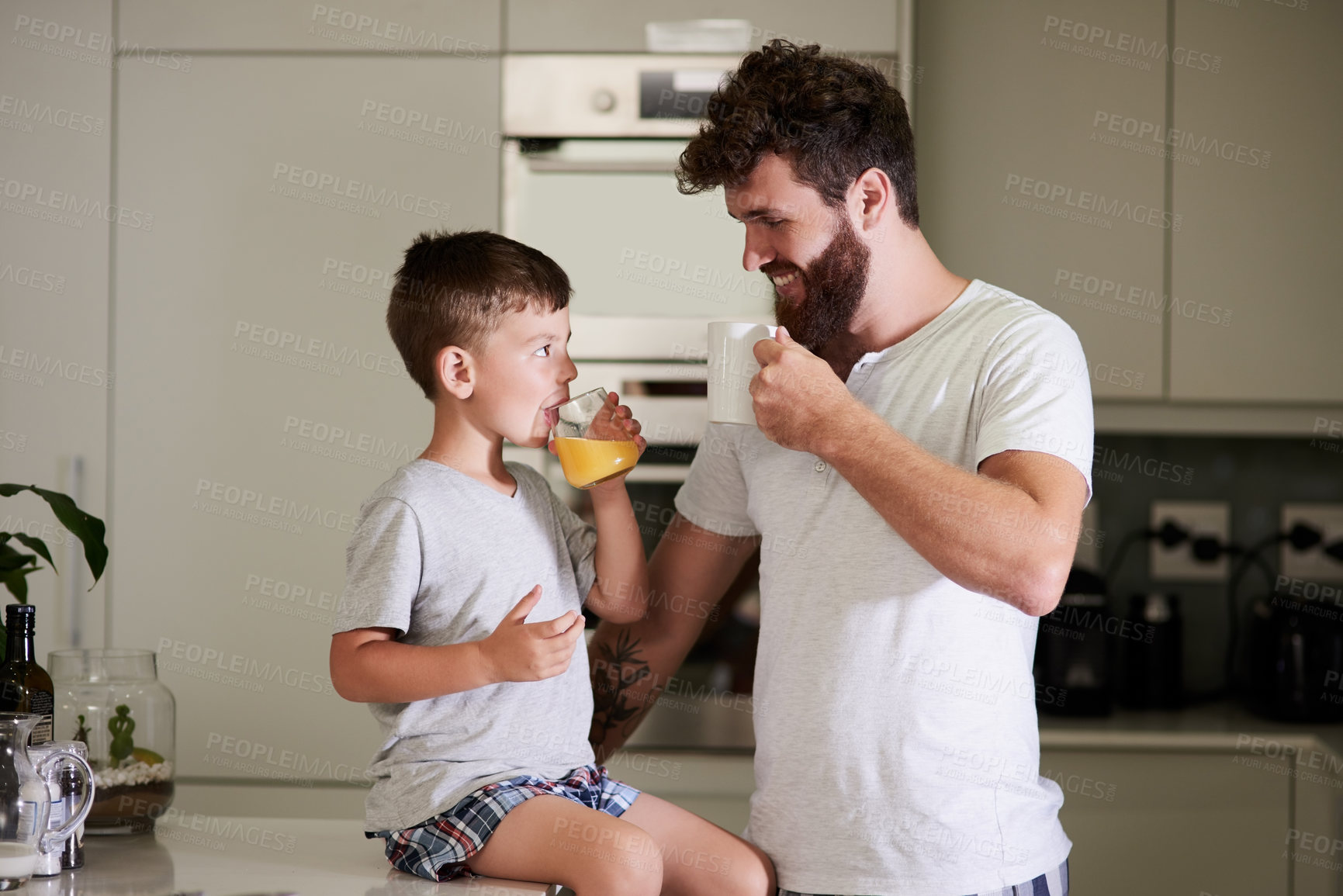 Buy stock photo Shot of an adorable little boy and his father having coffee and juice together at home