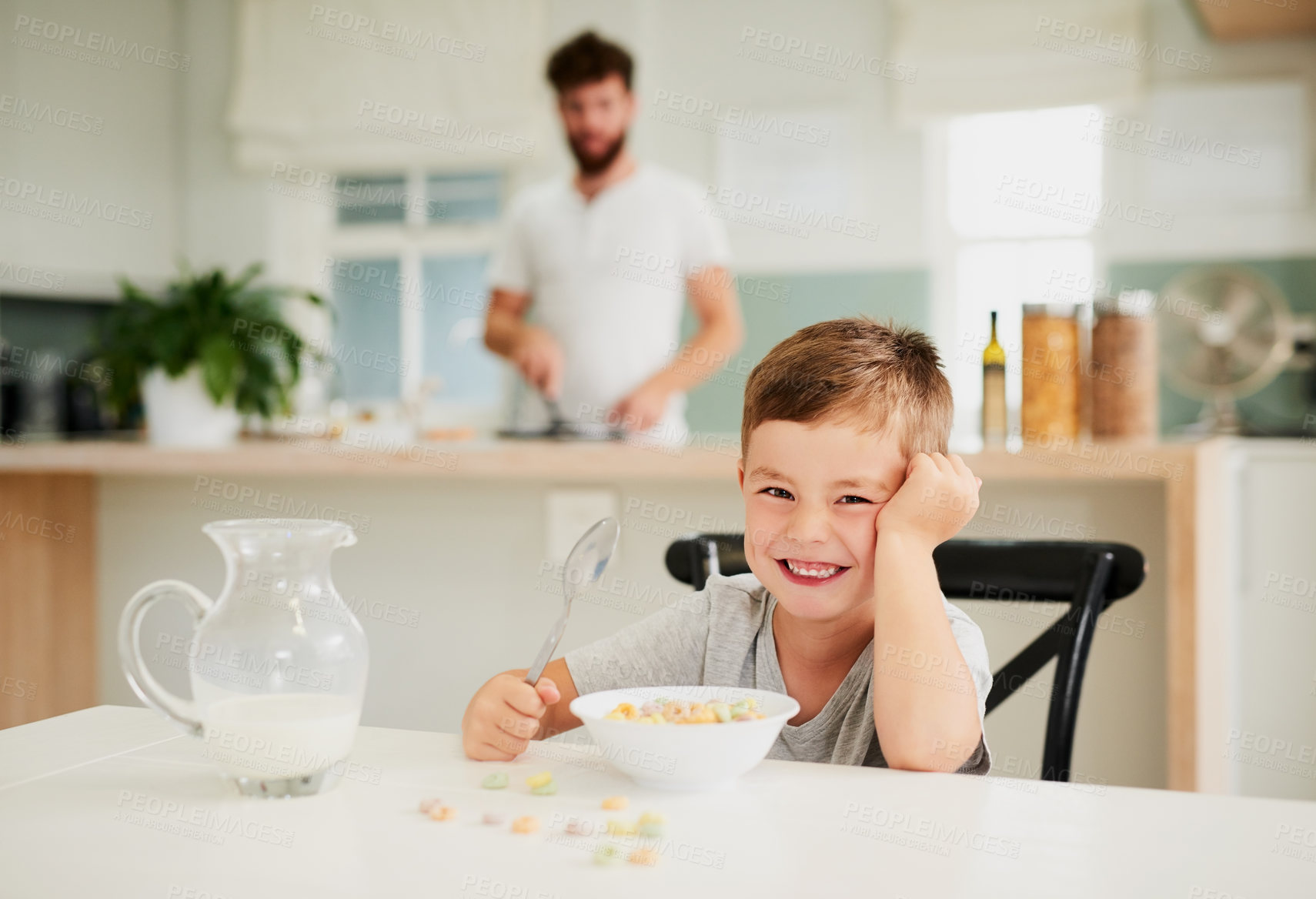 Buy stock photo Shot of an adorable little boy having breakfast with his father in the background at home