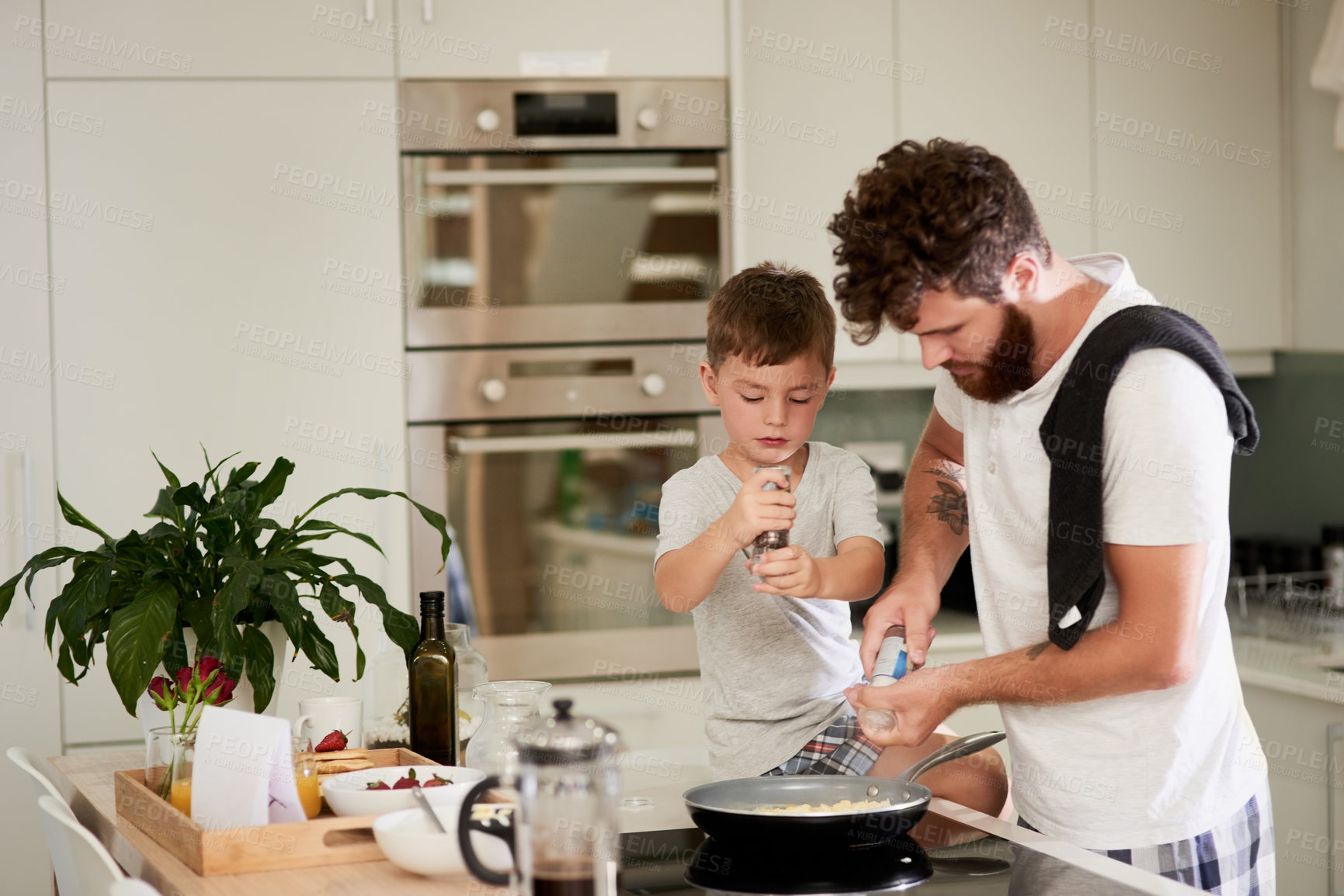 Buy stock photo Shot of an adorable little boy and his father making breakfast together at home