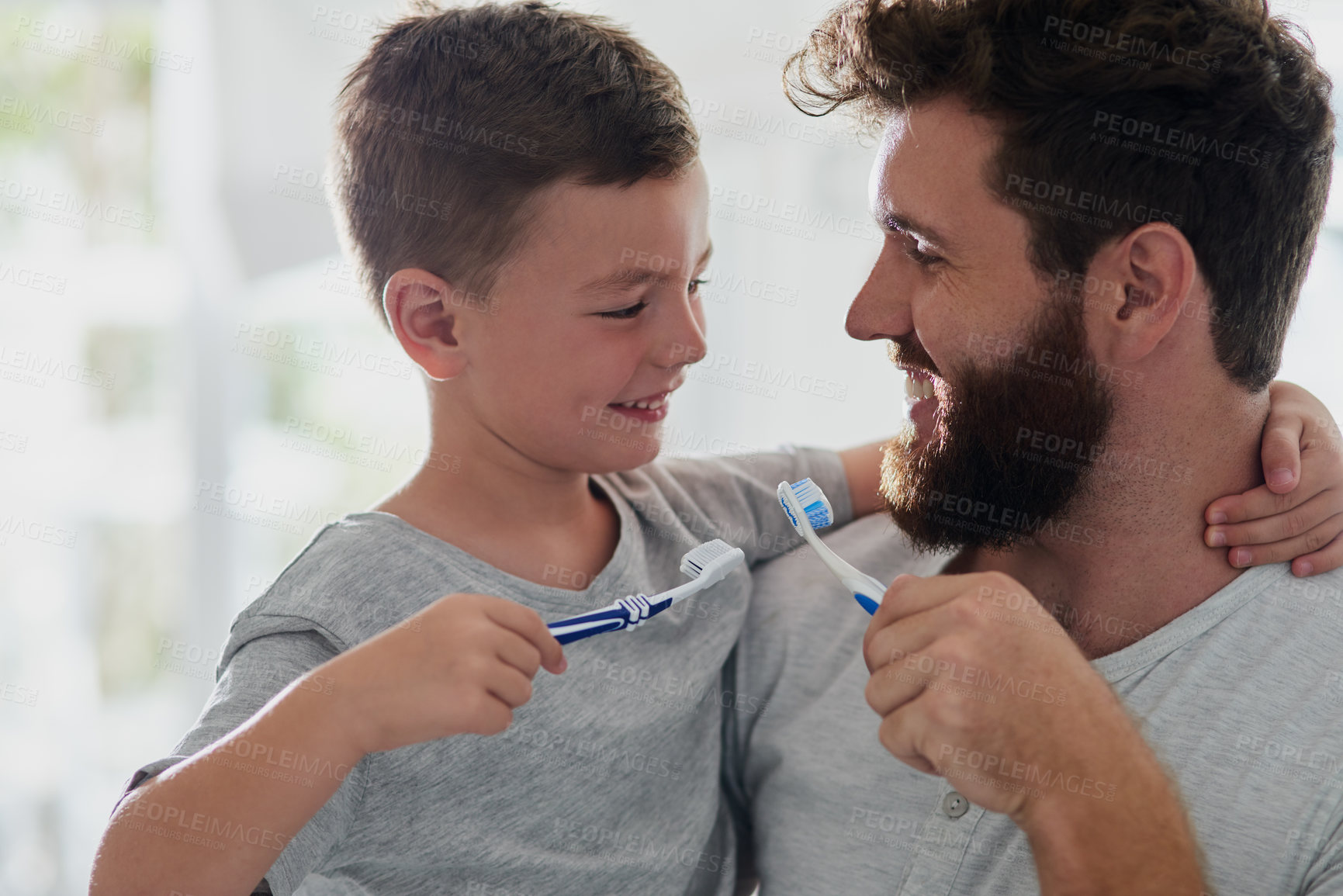 Buy stock photo Shot of a father and his little son brushing their teeth together in the bathroom at home