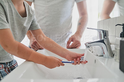 Buy stock photo Closeup shot of an unrecognizable little boy brushing his teeth with his father in the bathroom at home