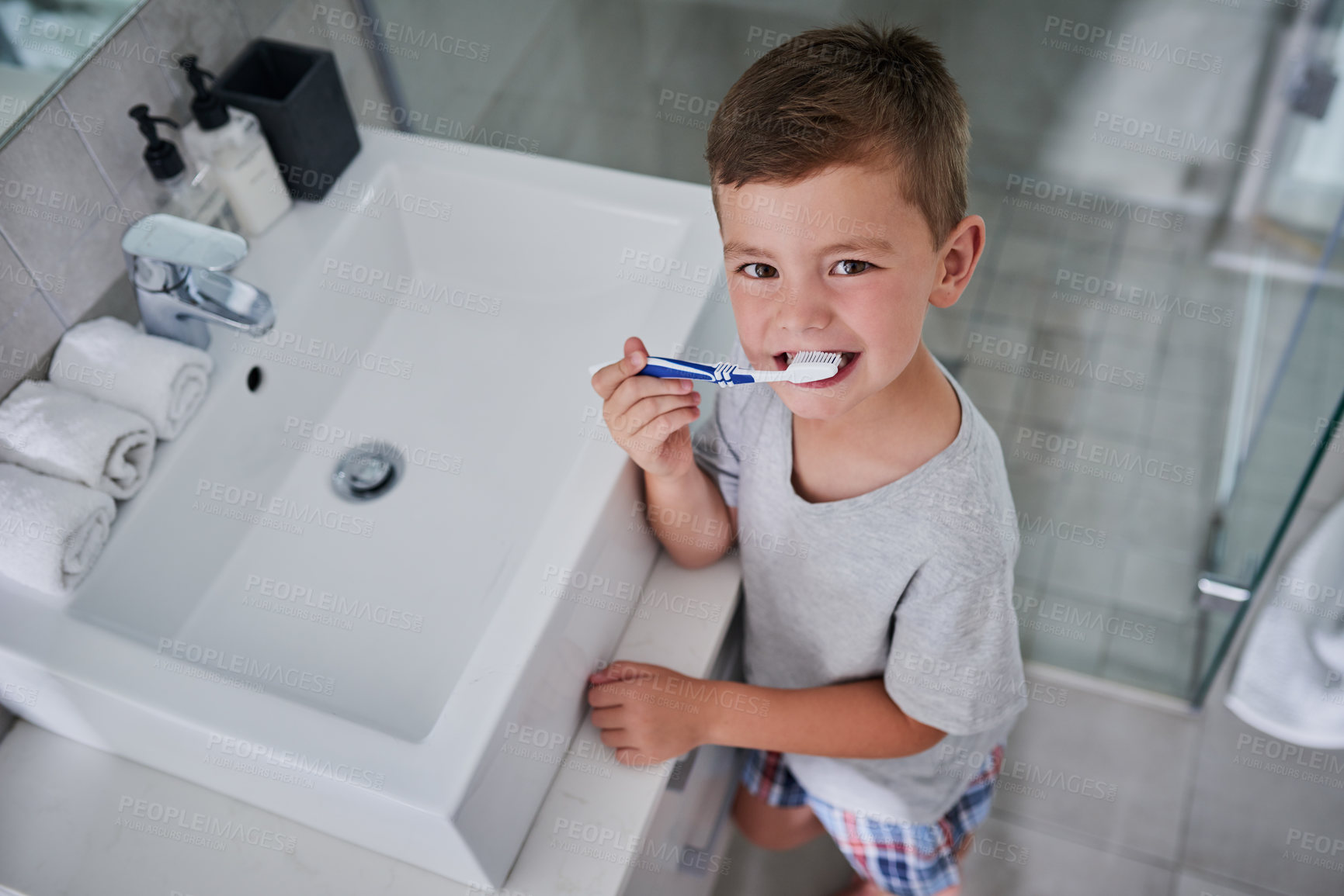 Buy stock photo Portrait of an adorable little boy brushing his teeth in the bathroom at home