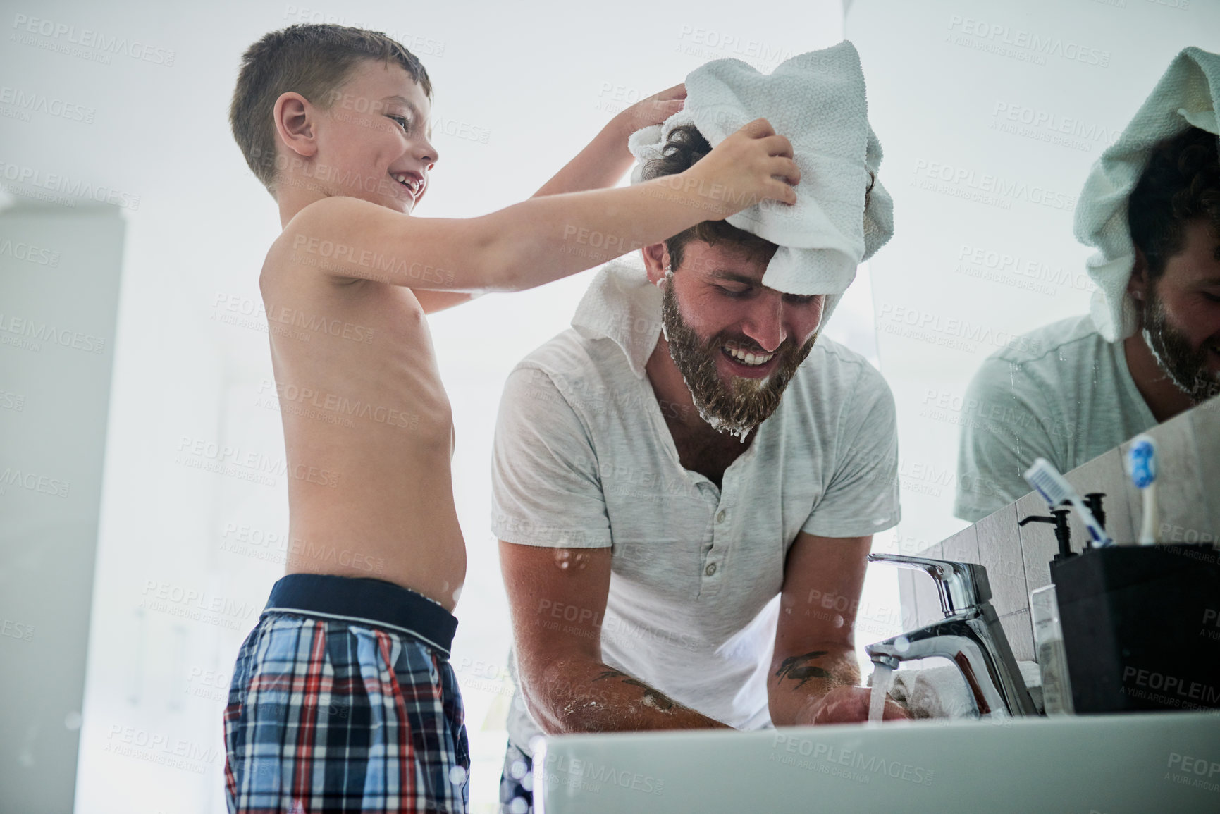 Buy stock photo Shot of a little boy wiping his father's head while shaving in the bathroom at home