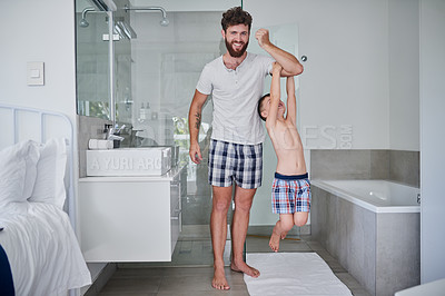 Buy stock photo Shot of a little boy hanging on his father's arm in the bathroom at home