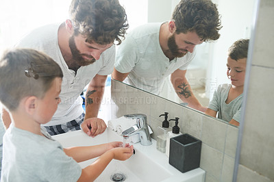 Buy stock photo Cropped shot of a young handsome father helping his adorable little boy wash his hands in the bathroom at home
