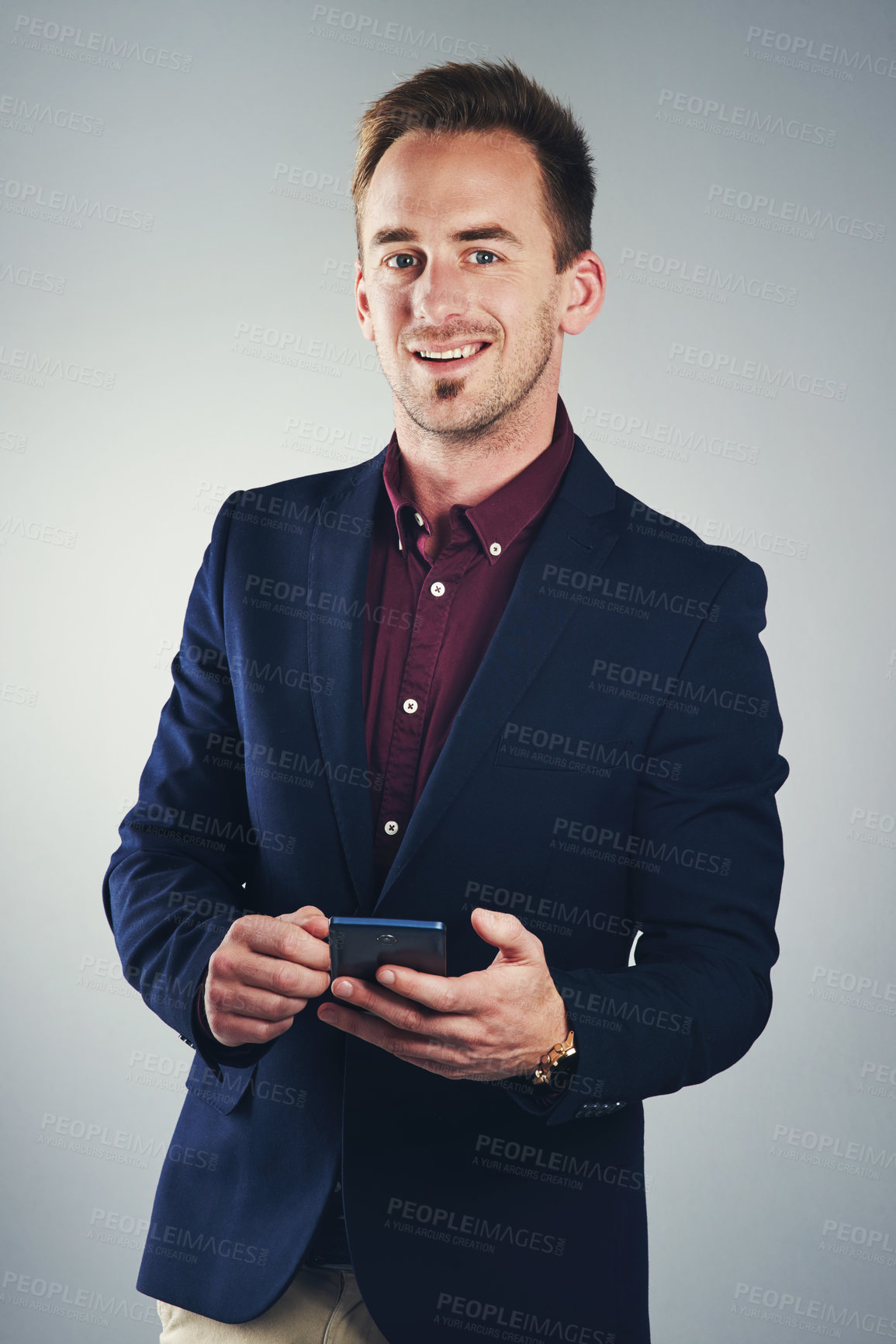 Buy stock photo Studio portrait of a confident young businessman using a mobile phone against a gray background