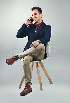 Buy stock photo Studio shot of a confident young businessman using a mobile phone against a gray background