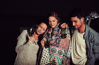 Buy stock photo Cropped shot of a group of friends having a drink on the beach at night