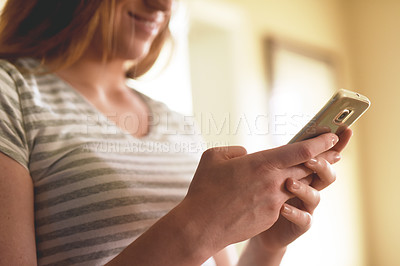 Buy stock photo Cropped shot of an unrecognizable woman using a cellphone in the morning at home
