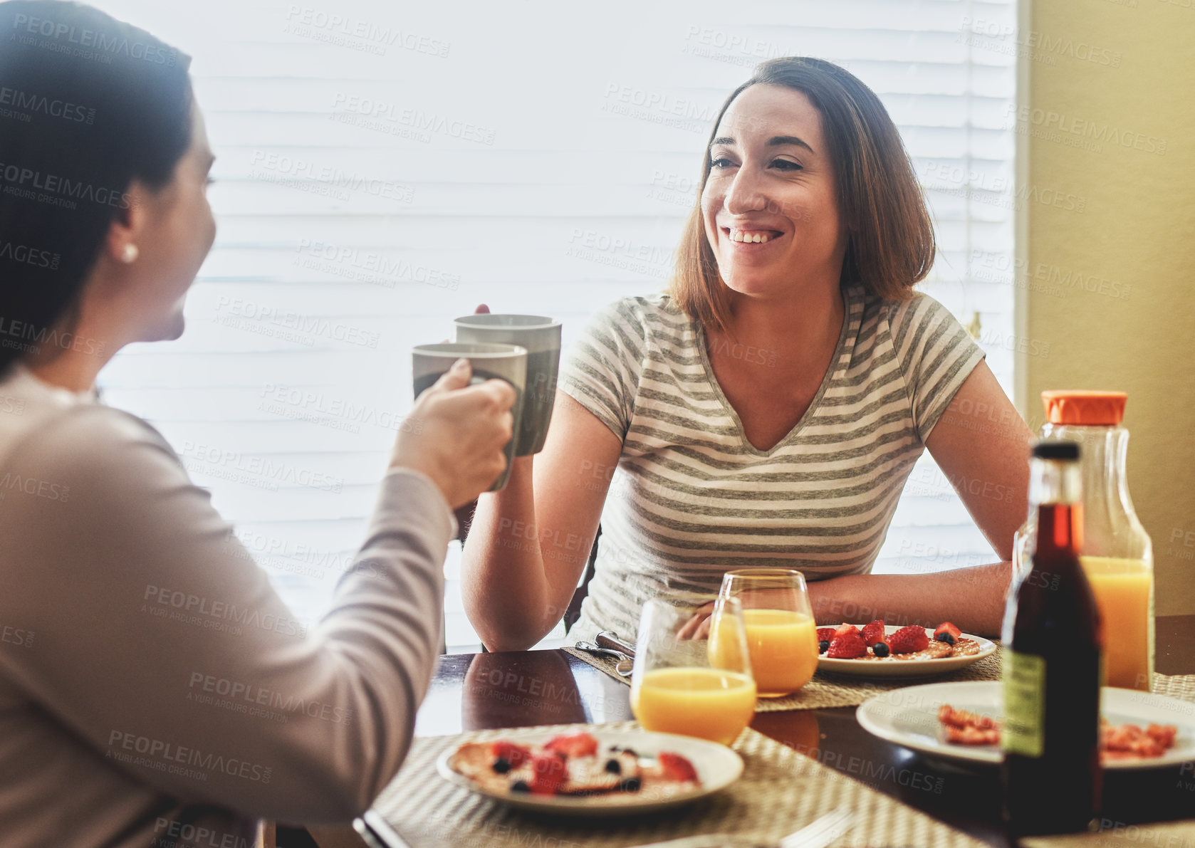 Buy stock photo Cropped shot of two young women having breakfast in the morning at home