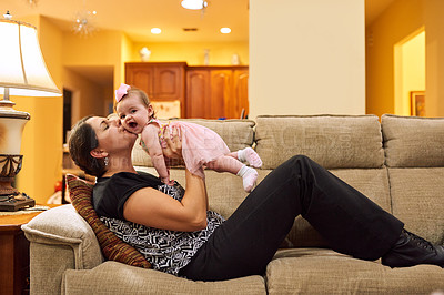 Buy stock photo Cropped shot of a mother picking up her adorable little baby daughter on the couch in the living room at home