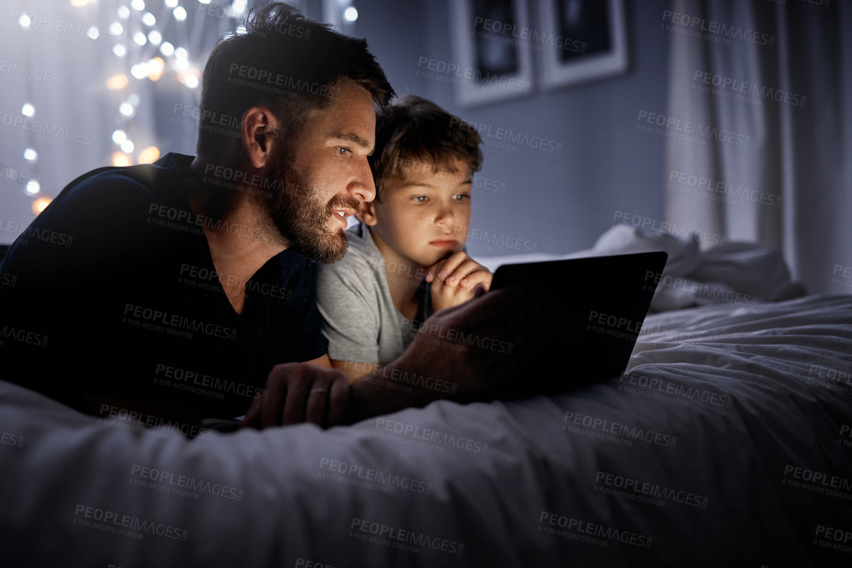 Buy stock photo Shot of a father and his little son using a digital tablet together in bed at night