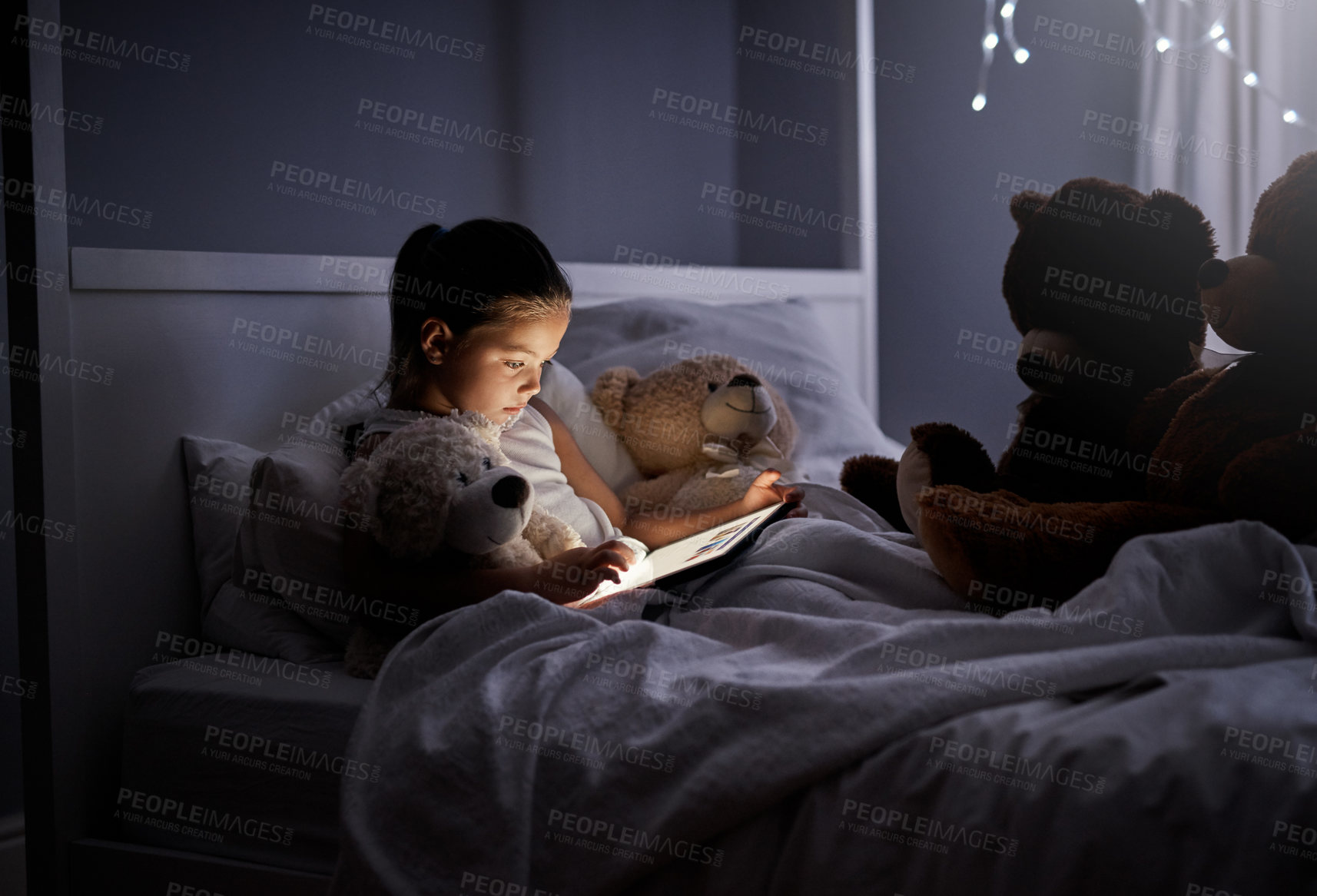 Buy stock photo Shot of an adorable little girl using a digital tablet in bed at night